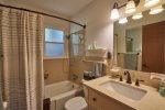 The bath has a combination tub/shower and sink, with shelves and towel bars.